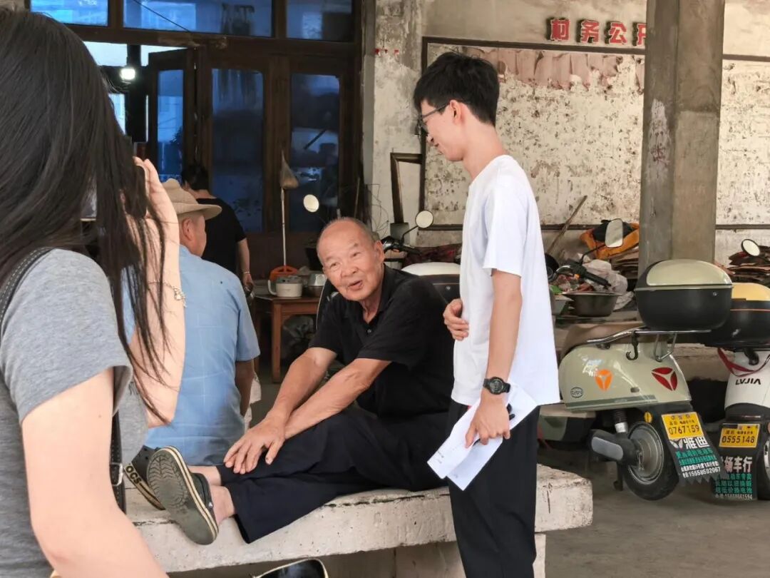 图为实践团成员在纳凉处与老人交流