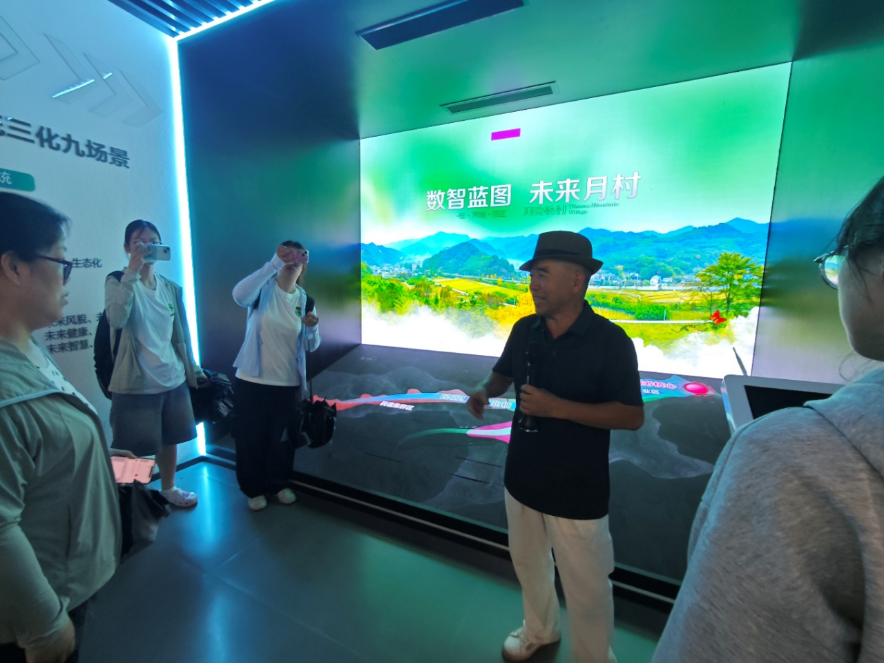 图2为叶国富讲解员介绍月亮桥村一核两轴四区发展规划